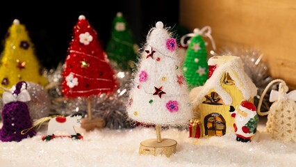 A delightful Christmas scene with a white handcrafted tree, ornaments, a yellow house, and a Santa figurine, encapsulating joyful winter wonderland vibes.