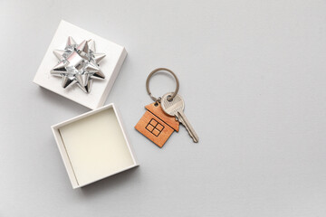 Gift box with key from house on grey background