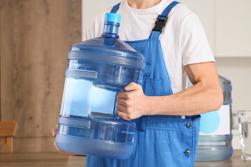 Delivery man with bottle of clean water in kitchen