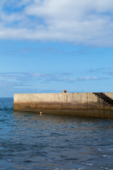 minimalistic beach landscape, walkway in Tenerife with a woman's handbag waiting while she swims