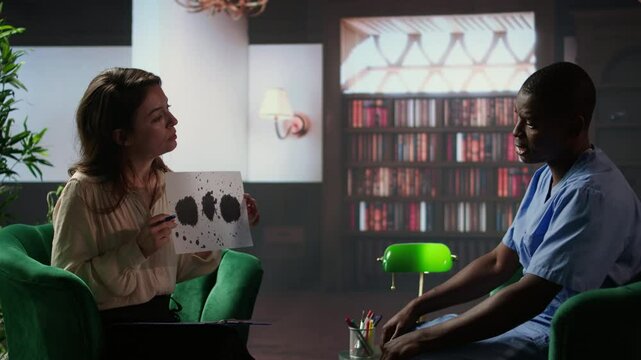 Counselor presents a Rorschach test to a medical assistant in uniform, looking for answers with psychoanalysis illustration. Nurse suffering from PTSD and trauma, interpretation therapy. Camera A.