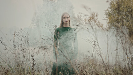 Fashion model posing in misty field wearing green