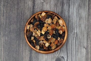 Mix of nuts and dried fruits in wooden bowl isolated on a wooden background.
