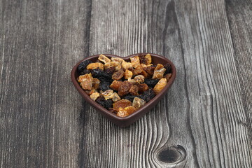Mix of nuts and dried fruits in wooden bowl isolated on a wooden background.