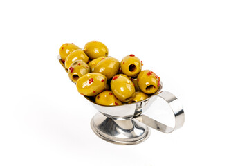 A metal gravy boat of spicy whole green Manzanillo olive with bits of red chili pepper isolated on white