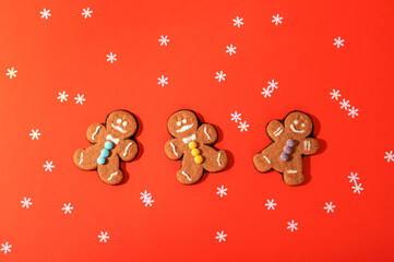 Gingerbread cookies on orange background with scattered white snowflakes for a festive holiday atmosphere. Christmas concept. Top view, flat lay