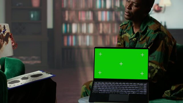 Military trooper studies Rorschach inkblot illustration next to green screen in therapy with psychologist, addressing PTSD and trauma recovery problems. Psychological support. Camera B.