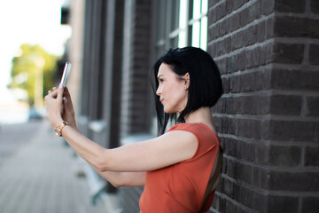 Confident woman taking a selfie or making a video call with a smartphone outdoors. 