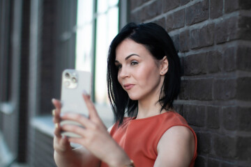 Confident woman taking a selfie or making a video call with a smartphone outdoors. 