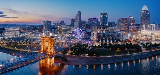 Cincinnati skyline at twilight, illuminated by city lights reflecting on the river. Iconic Roebling...