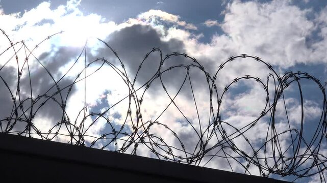 USA - 7.11.2024 - Low angle view of prison barbed wire backed by sunlight.