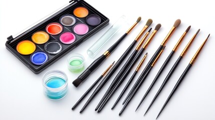 Naklejka premium Watercolor paints, brushes, and containers arranged on white background.