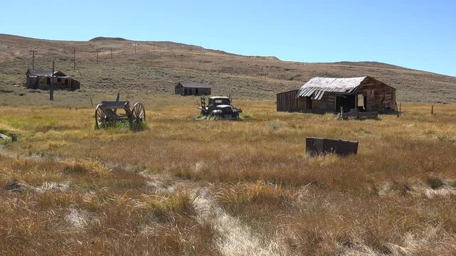BODIE - 10.21.2024 - A wagon, truck, and run-down wooden building sit in the abandoned boomtown of Bodie, California.
