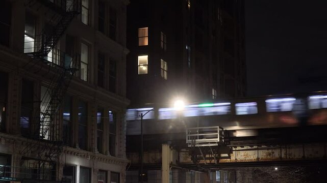 CHICAGO - 12.5.2024 - An elevated train exits a passage between apartment buildings in Chicago at night.