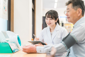 病院・クリニックで人間ドック・健康診断する男性と医師（血圧）
