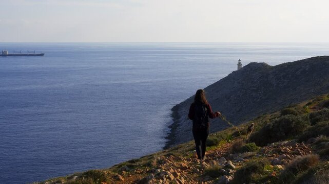 Woman with dog walking to Cape Tainaron Matapan Lighthouse the southernmost point of Greece and second from Europe