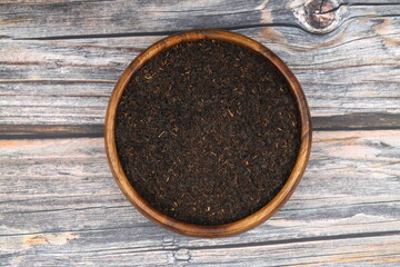 Dry black tea leaves isolated on wooden background, top view