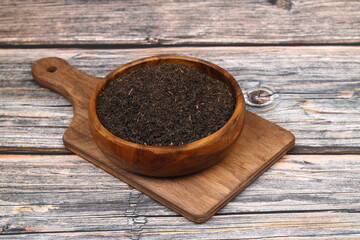 Dry black tea leaves isolated on wooden background, top view