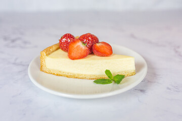 Classic sliced homemade New York cheesecake with fresh strawberries served on a marble countertop. Homemade dessert.  
