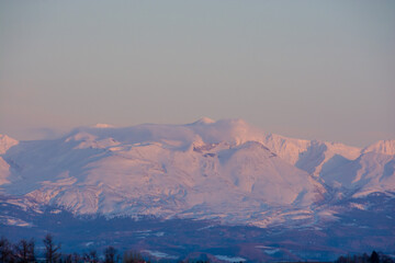 夕陽を反射する雪の火山の山頂　十勝岳
