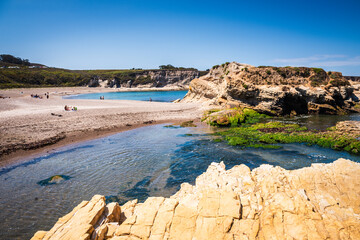 Tidal pool and beach framed by rock formations at Montaña de Oro State Park in California.