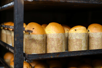A rack of bread loaves with a paper wrapper around them, Easter baking at the factory