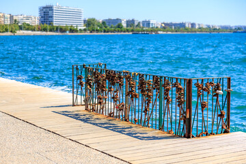 A metal fence with flowers on it is next to a body of water