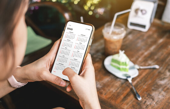 Businesswoman using smartphone with monthly calendar to plan 2025 activities. Scheduling and organizing plans. Technology and business concept.