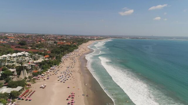 Aerial view sand beach with resting people, hotels and tourists, sun umbrellas, Bali, Kuta. surfers on water surface. Seascape, beach, ocean, sky sea Travel concept