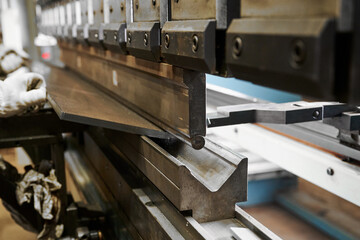 Bending machine operates with heavy metal plate in shop