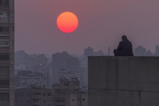 A dramatic shot of an imam calling the adhan (call to prayer) at sunset, signaling the time for iftar