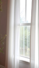 Fototapeta premium A window with sheer white curtains gently billowing in the spring breeze, maintain a soft and muted color scheme to convey a sense of tranquility and simplicity, photo