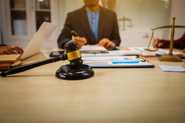 Two male and female lawyers sit at a table in an office, discussing legal matters related to...
