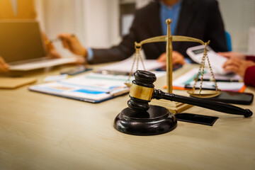 Two male and female lawyers sit at a table in an office, discussing legal matters related to...