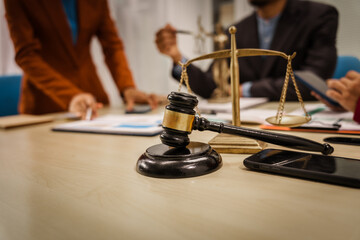 Two male and female lawyers sit at a table in an office, discussing legal matters related to...