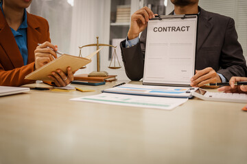 Two male and female lawyers sit at a table in an office, discussing legal matters related to...