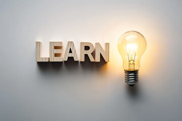 The word "LEARN" made of wooden cubes placed on a white surface, a light bulb glowing brightly next to it, leaving space for a motivational quote.