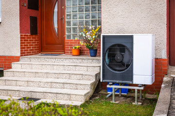 Air source heat pump installed outside of old renovated house, green renewable energy concept of...