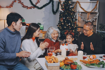 Multi-Generation Family Celebrate Christmas At Home Wearing Santa Hats And Antlers Opening Presents