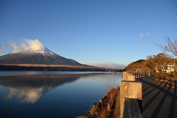 山中湖の湖面と散策路と雲がかかった富士山の風景