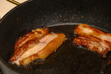 Sizzling bacon strips cooking to perfection in a frying pan on a warm kitchen stovetop