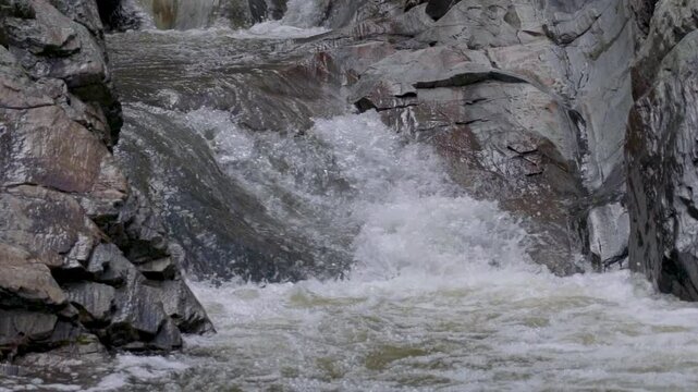 slow motion of waterfall water flowing between rocks in nature in winter season