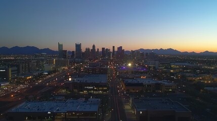 Fototapeta premium A sunset view of a city skyline with mountains in the background.
