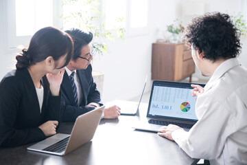 Several businessmen in work clothes in a beautifully backlit office explaining computer statistics on architecture, construction, etc.