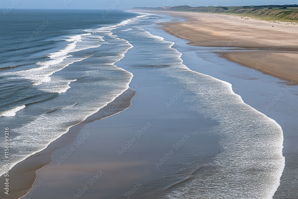 Poster aerial view of a wide sandy beach with gentle waves rolling ashore on a sunny day.
