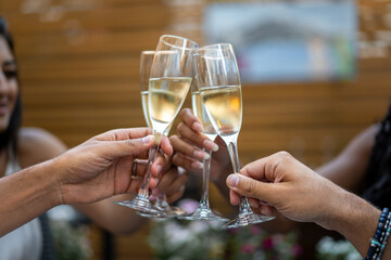 Close-up of hands clinking champagne glasses during outdoor celebration