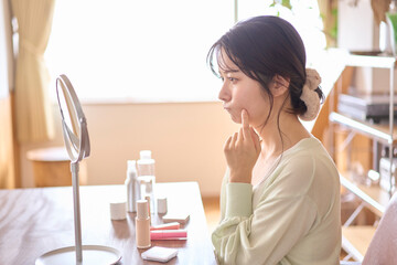 鏡を見ながら顔を触る女性。