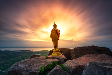 Golden buddha statue standing on the edge and saw the large and wide Pa Sak Chonlasit Dam of  Khao Phraya Dern Thong Viewpoint with the beautiful sunrise at Lopburi province, Thailand.
