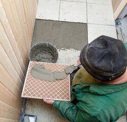 A man is laying tiles on a floor