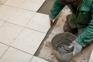 A man is laying tiles on a floor